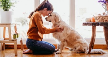 Woman hugging her golden retriever dog at home